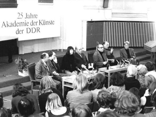 Günther Rücker (5.v.li.) bei einer Schriftstellerlesung der Akademie der Künste der DDR am 10.4.75 | Bildquelle: Bundesarchiv, Bild 183-P0411-0022, via Wikimedia Commons/S. Kutscher (verehe. Kubiziel)/CC BY-SA 3.0, https://creativecommons.org/licenses/by-sa/3.0/de/deed.en Mehrere Menschen an einem Podium vor einer Zuhörerschaft, schwarz-weiß